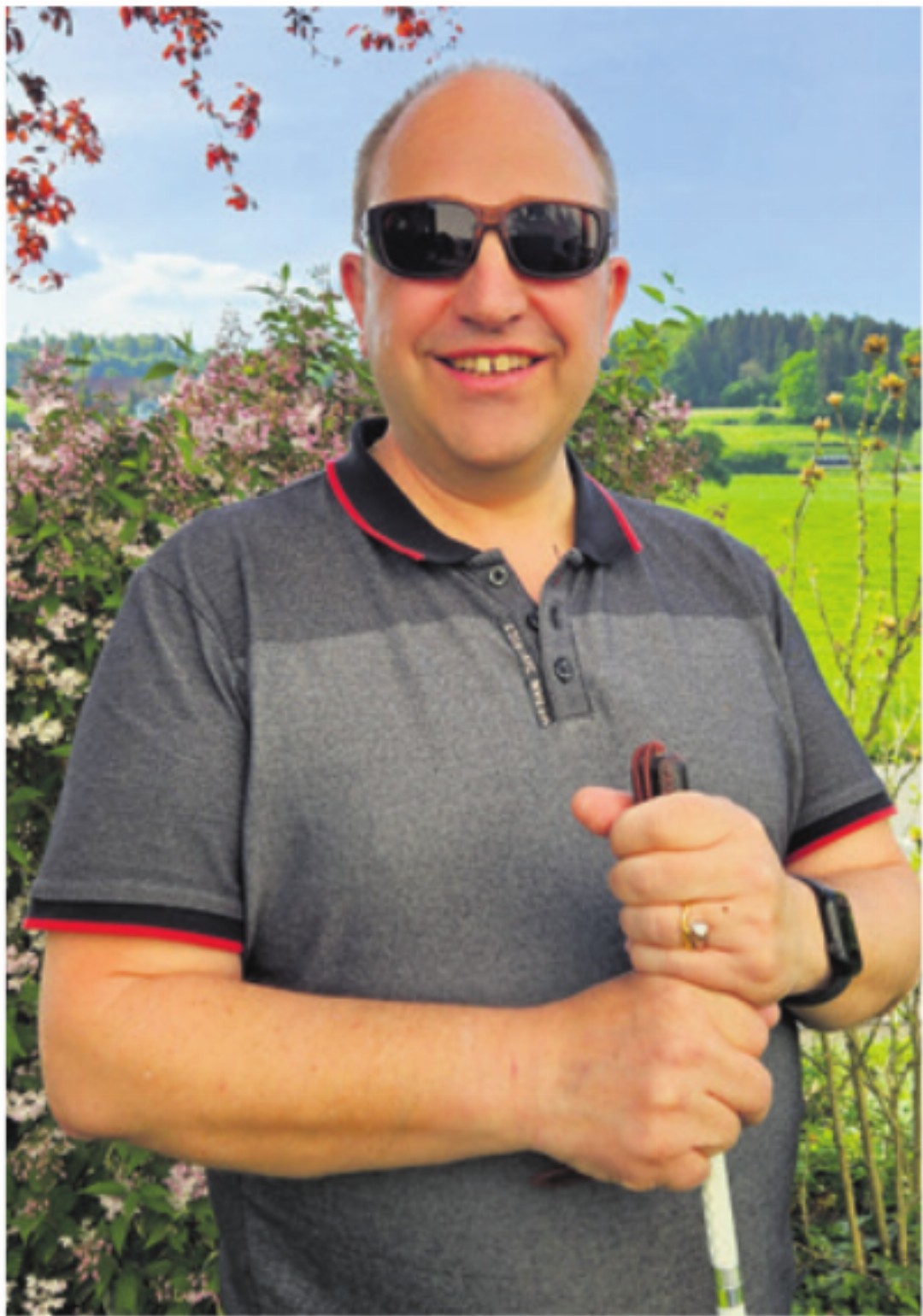 Roger Meyrat mit Kantenfilterbrille und Langstock im heimischen Garten. Roger Meyrat mit Kantenfilterbrille und Langstock im heimischen Garten.